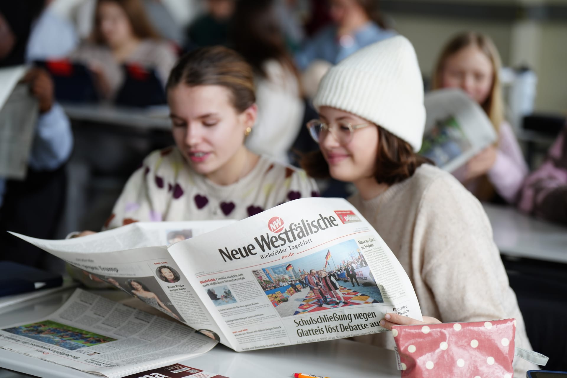 Schülerinnen lesen gemeinsam die Neue Westfälische im Unterricht