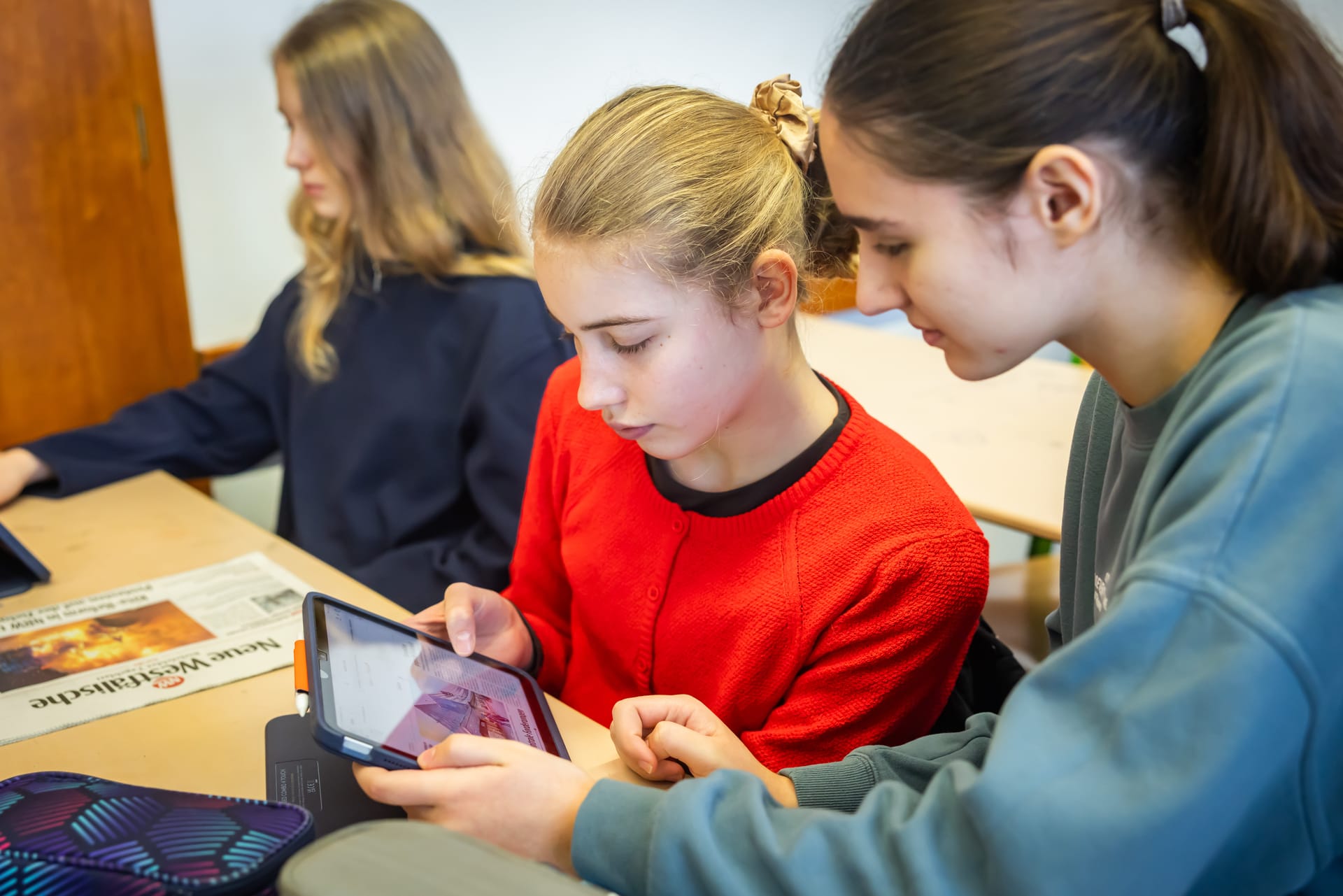 Schülerinnen arbeiten gemeinsam mit einem Tablet im Unterricht